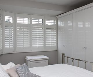 Bay window shutters in bedroom